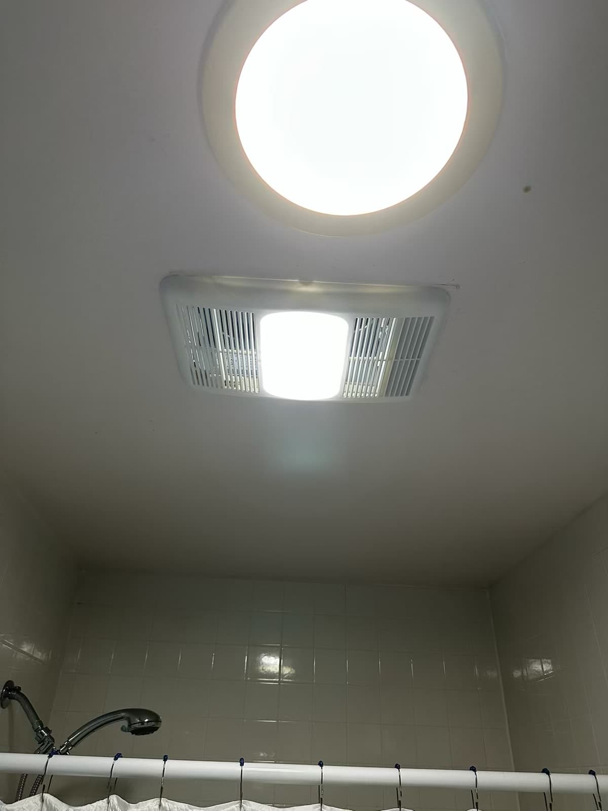 Bathroom ceiling exhaust fan unit with its light illuminated on the Christiansburg job